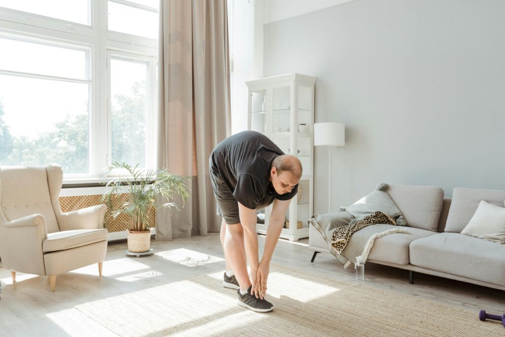 Un hombre de mediana edad realiza ejercicios de estiramientos en el salón de una casa,