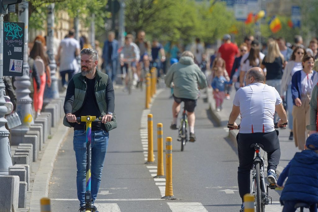 Usuarios de patinetes y bicicletas circulando por carriles específicos en una ciudad.